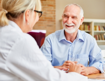 a senior man smiling in conversation with a woman