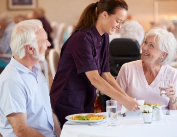 a server smiles while delivering plates to a table