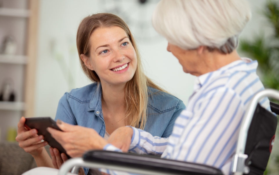 a consulting dietician kneels down to talk with a senior woman in a wheel chair about dietary needs